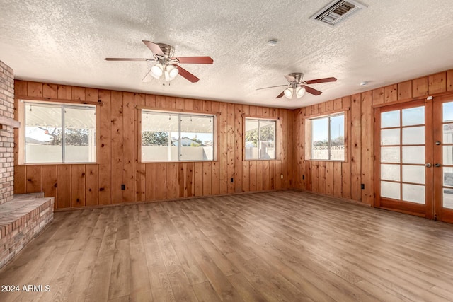 interior space with a textured ceiling, light hardwood / wood-style flooring, and wood walls