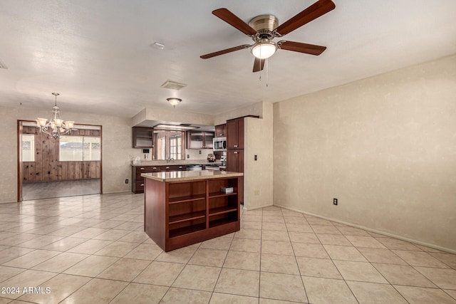 kitchen with dark brown cabinetry, stainless steel appliances, pendant lighting, light tile patterned flooring, and ceiling fan with notable chandelier