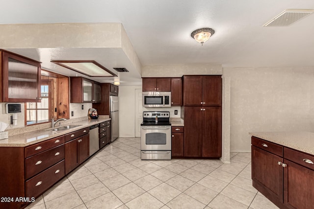 kitchen featuring light stone counters, light tile patterned floors, sink, and appliances with stainless steel finishes