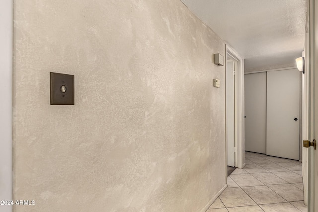 corridor featuring light tile patterned floors and a textured ceiling