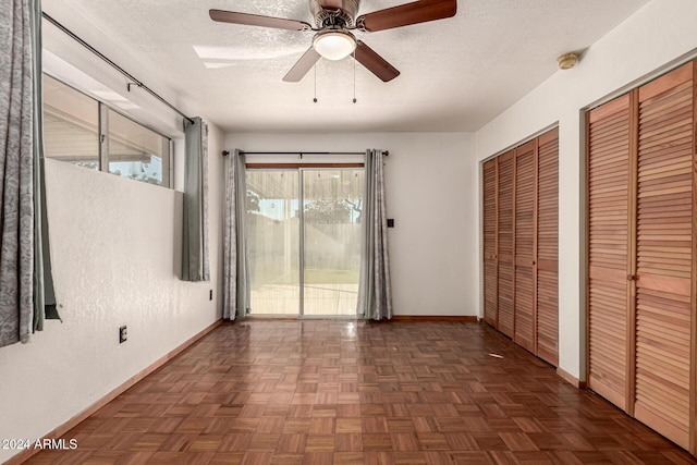 unfurnished bedroom with dark parquet floors, access to outside, ceiling fan, and multiple closets