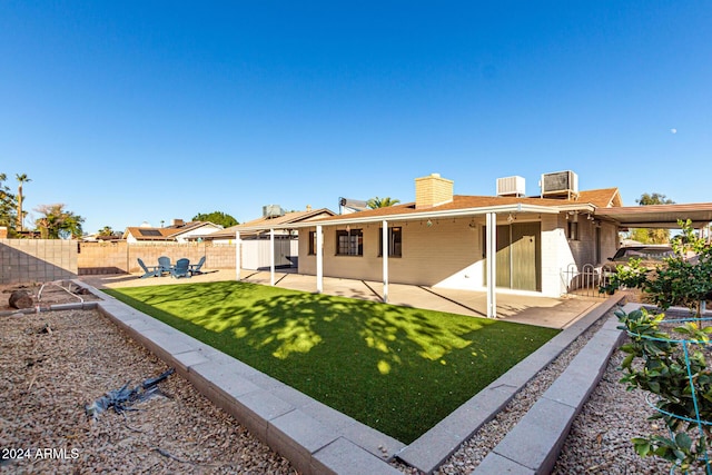 rear view of property with a lawn, cooling unit, and a patio area