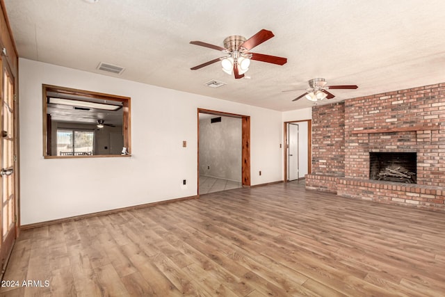 unfurnished living room featuring hardwood / wood-style floors, a textured ceiling, and a brick fireplace