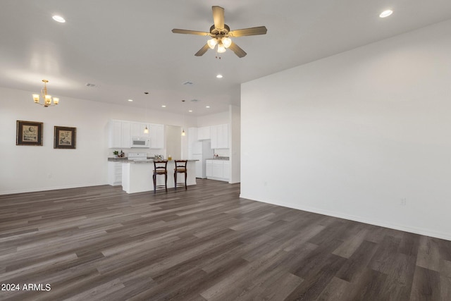 unfurnished living room featuring dark hardwood / wood-style floors and ceiling fan with notable chandelier