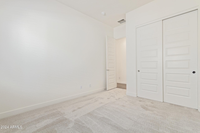 unfurnished bedroom with light carpet and a closet