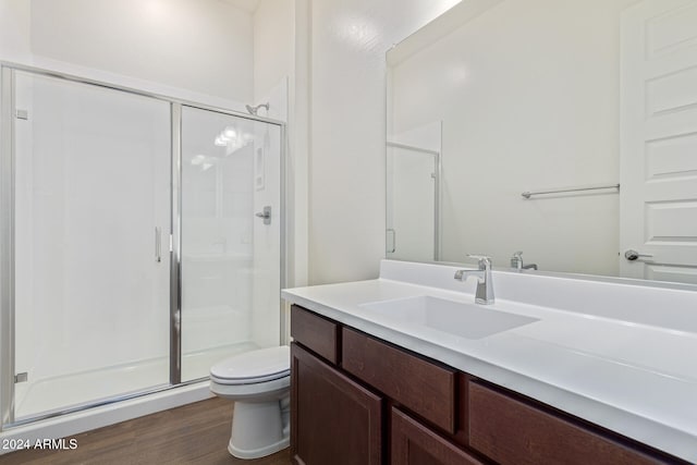 bathroom featuring vanity, toilet, wood-type flooring, and a shower with door