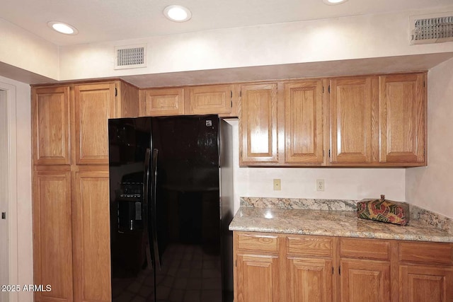 9115 N 101st Way, Scottsdale, AZ 85258 - kitchen featuring black fridge with ice dispenser, light stone counters, and brown cabinetry