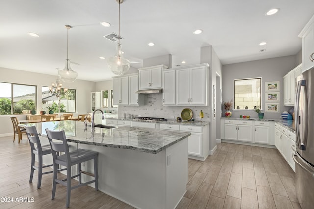 kitchen with light hardwood / wood-style flooring, white cabinetry, decorative light fixtures, and sink