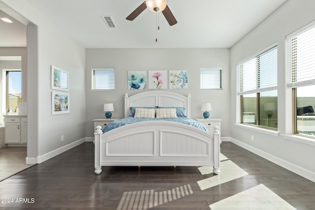 bedroom featuring ceiling fan, ensuite bath, and dark wood-type flooring