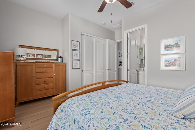 bedroom featuring a closet, ensuite bath, light hardwood / wood-style floors, and ceiling fan