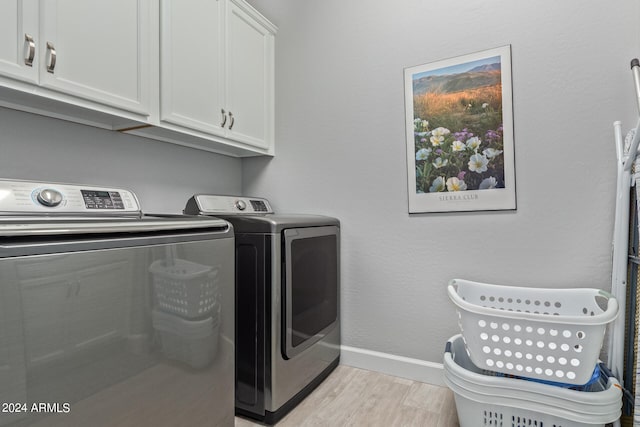 laundry area with washer and clothes dryer, cabinets, and light wood-type flooring