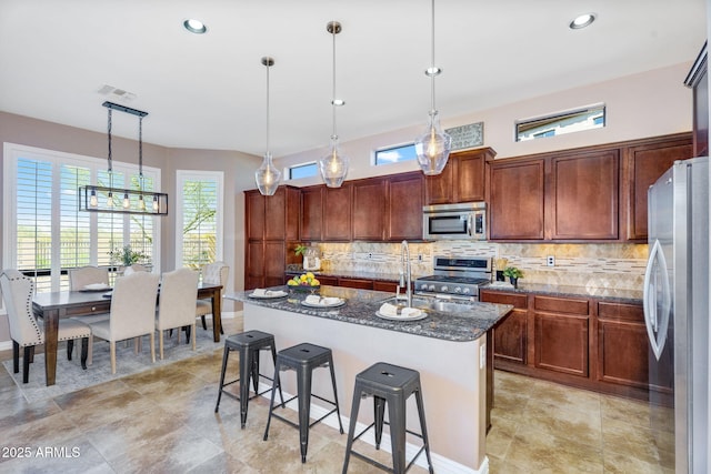kitchen with visible vents, a breakfast bar, decorative backsplash, dark stone countertops, and appliances with stainless steel finishes