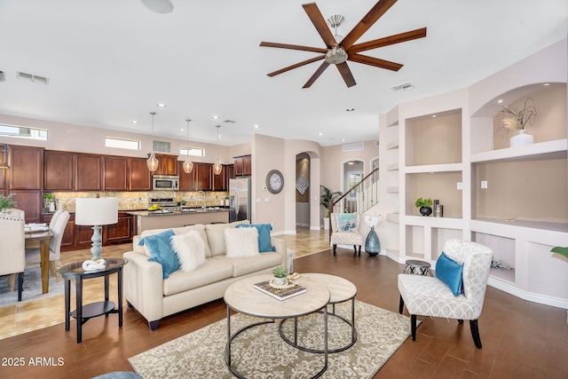 living area with visible vents, built in shelves, ceiling fan, and wood finished floors