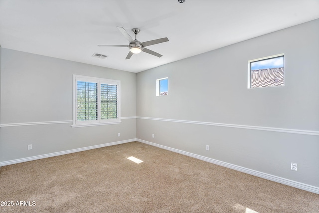 unfurnished room with visible vents, carpet flooring, a ceiling fan, and baseboards