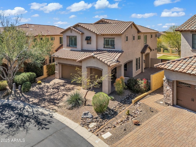 mediterranean / spanish house with a tiled roof, a garage, and stucco siding