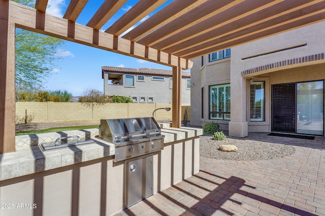 view of patio with grilling area, a fenced backyard, a pergola, and exterior kitchen