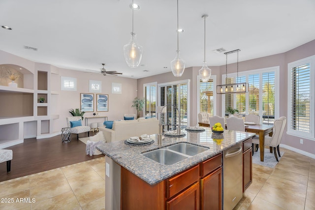 kitchen with visible vents, built in shelves, open floor plan, light tile patterned floors, and a sink