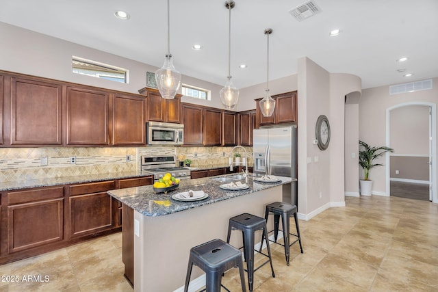kitchen with arched walkways, visible vents, stainless steel appliances, and a sink