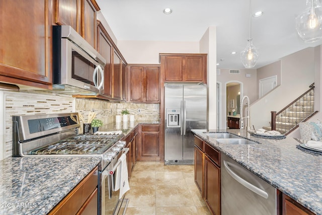 kitchen with visible vents, a sink, dark stone countertops, backsplash, and stainless steel appliances