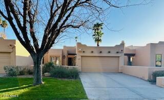 pueblo-style home featuring a front lawn