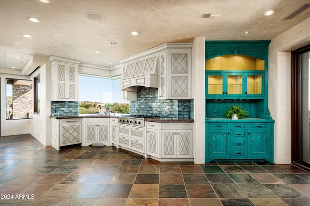 kitchen with white cabinetry, stainless steel gas stovetop, sink, and backsplash