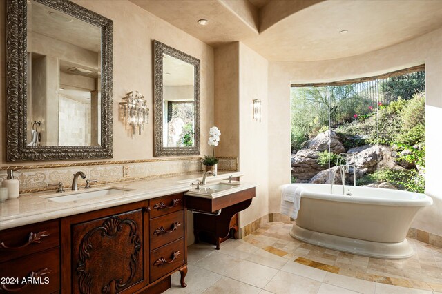 bathroom featuring a wealth of natural light, a tub to relax in, vanity, and backsplash