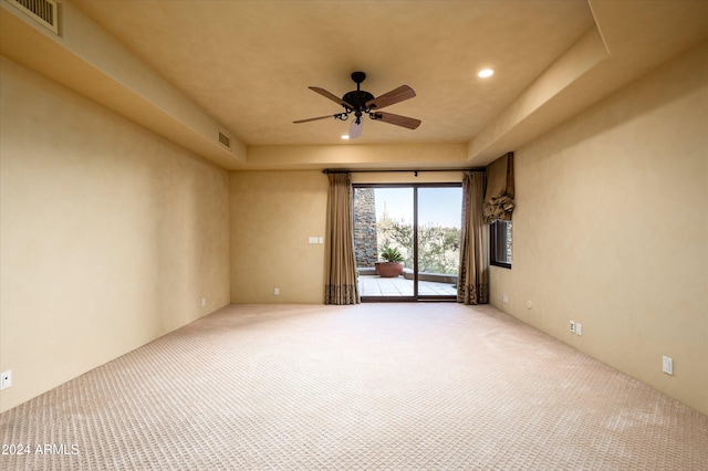 empty room featuring ceiling fan, a tray ceiling, and light colored carpet