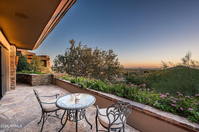 balcony at dusk featuring a patio area