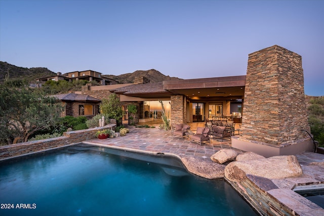 pool at dusk featuring a jacuzzi and a patio