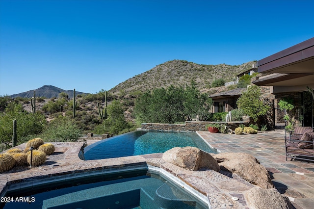 view of swimming pool featuring a patio area, a mountain view, and an in ground hot tub