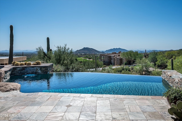 view of swimming pool featuring a patio, a mountain view, and pool water feature