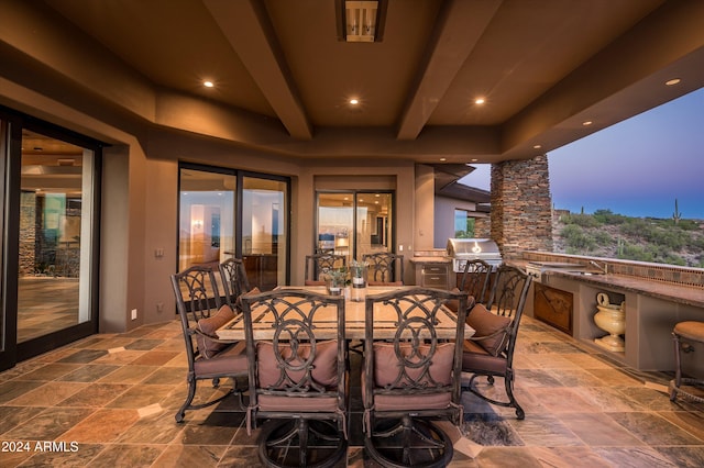 patio terrace at dusk with grilling area, sink, and exterior kitchen