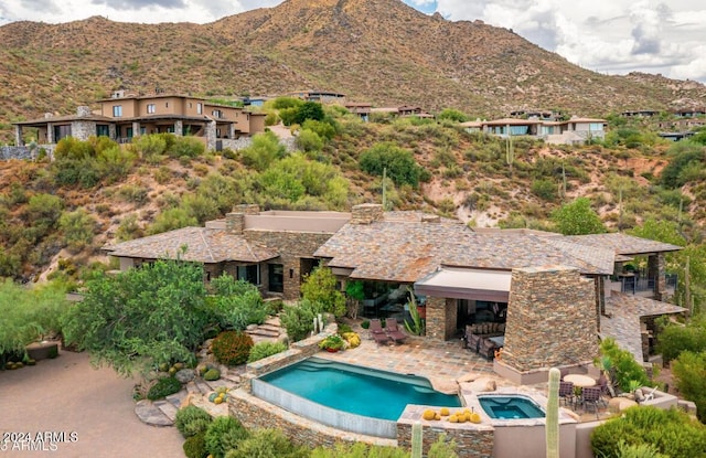 view of swimming pool with a patio, a mountain view, and an in ground hot tub