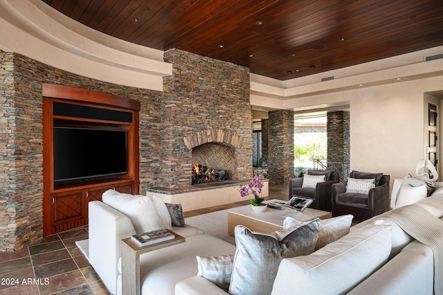 living room featuring wooden ceiling and an outdoor stone fireplace