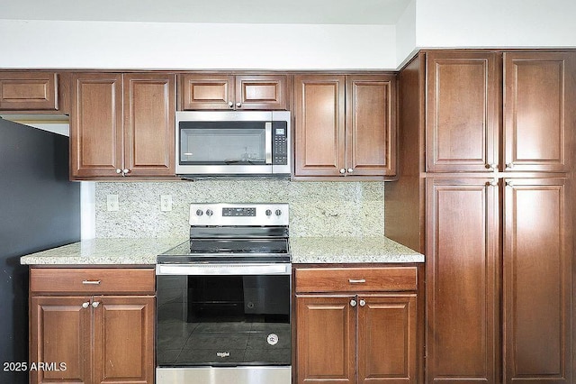 kitchen featuring stainless steel appliances, light stone counters, and tasteful backsplash