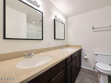 bathroom with double vanity, a sink, tile patterned floors, and toilet
