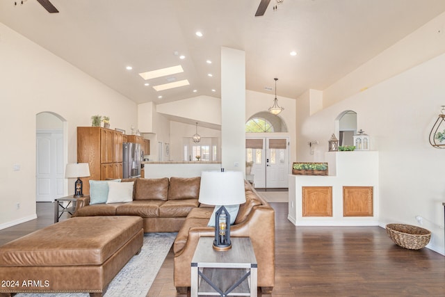 living room with ceiling fan, wood-type flooring, a skylight, and high vaulted ceiling