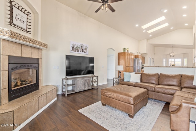 living room featuring dark wood-type flooring, ceiling fan, a tile fireplace, and high vaulted ceiling