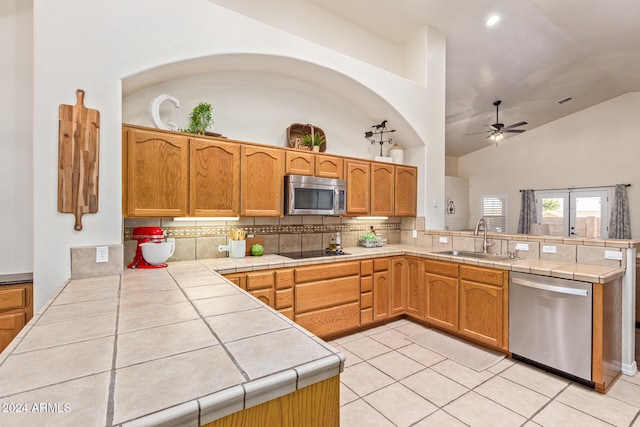 kitchen with kitchen peninsula, tile counters, sink, and appliances with stainless steel finishes