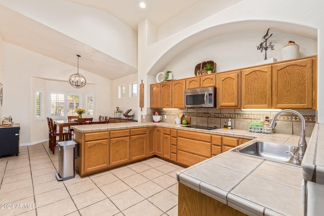 kitchen featuring black electric stovetop, kitchen peninsula, hanging light fixtures, sink, and high vaulted ceiling