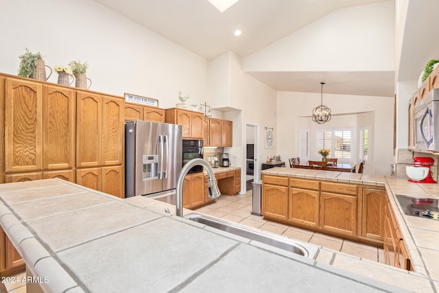 kitchen featuring tile counters, high vaulted ceiling, black appliances, and pendant lighting