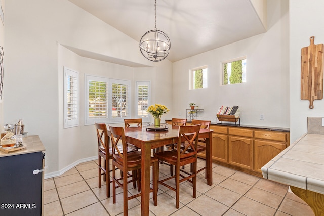 tiled dining space featuring high vaulted ceiling and a chandelier