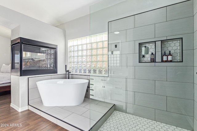 bathroom with a tub to relax in, tile walls, and wood-type flooring