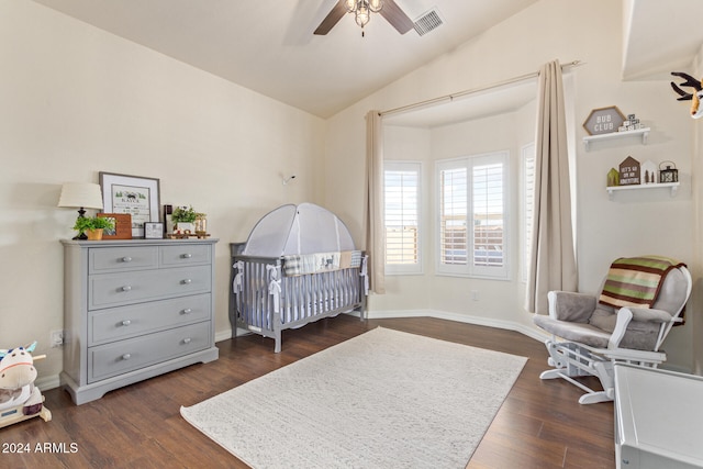 bedroom featuring a crib, dark wood-type flooring, ceiling fan, and lofted ceiling