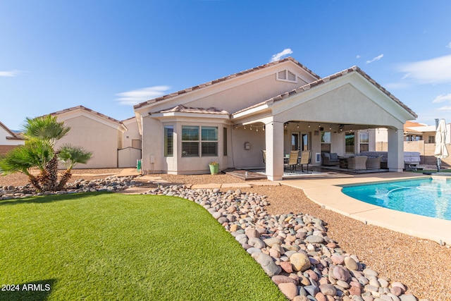 rear view of house with ceiling fan, a yard, and a patio area