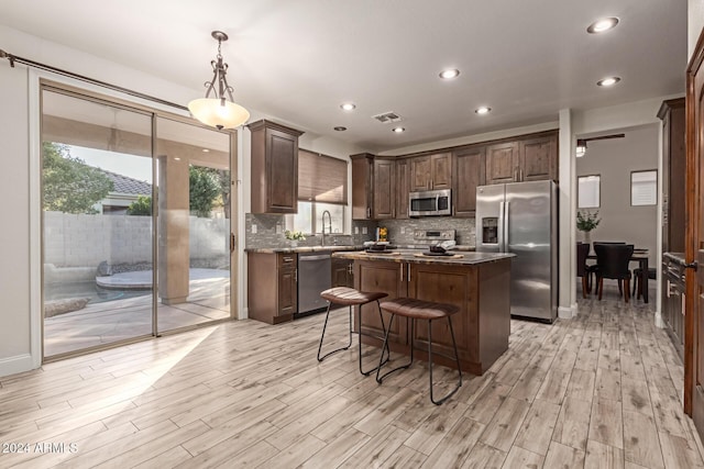 kitchen featuring a center island, sink, decorative light fixtures, light hardwood / wood-style floors, and stainless steel appliances