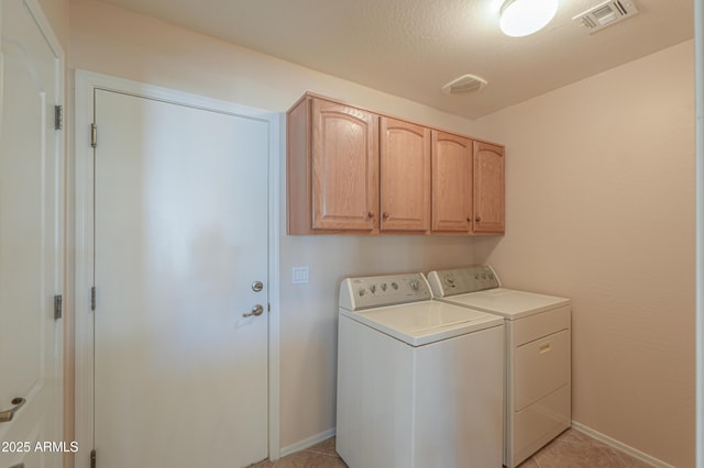 clothes washing area featuring cabinets, light tile patterned floors, washer and dryer, and a textured ceiling