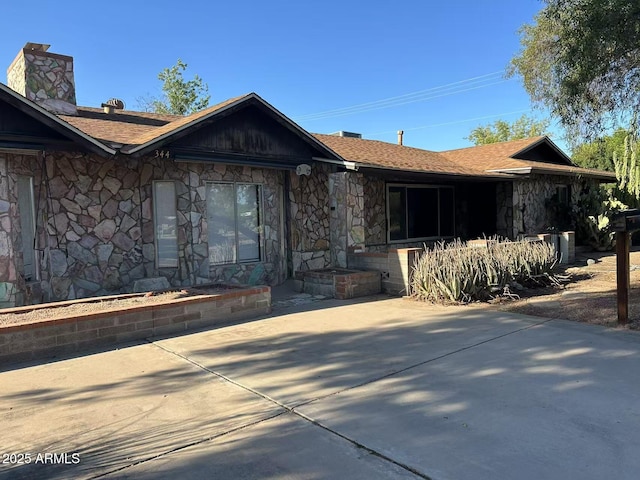 344 E Aepli Dr, Tempe, AZ 85282 - view of front facade featuring stone siding, a chimney, a patio, and a shingled roof