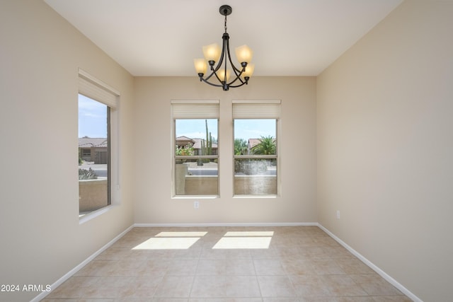 unfurnished room with light tile patterned floors, a wealth of natural light, and a chandelier