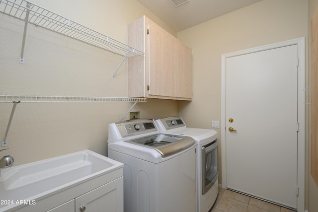 washroom with sink, cabinets, washing machine and clothes dryer, and light tile patterned flooring